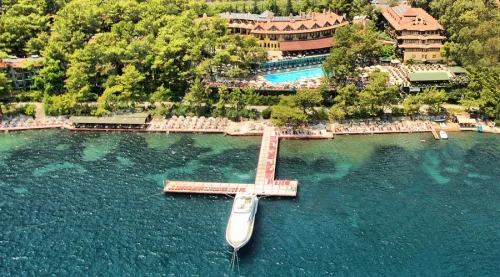 Dalaman Havalimanı'ndan Marmaris Park Hotel'e ulaşım sağlayan Ege Vip Tur lüks transfer aracı ve çam ağaçları arasındaki otel girişi manzarası.
