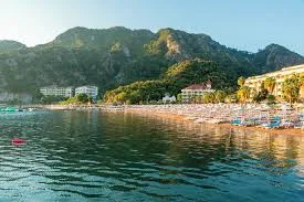 Ein luxuriöser Mercedes Vito für den VIP-Transport vom Flughafen Dalaman in die Region Marmaris İçmeler, im Hintergrund die mit Pinien bewachsene Bucht von İçmeler und das Hotel Orka Lotus Beach.