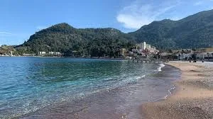 Dalaman Havalimanı'ndan Marmaris Turunç bölgesine VIP transfer sağlayan siyah lüks Mercedes Vito araç, arka planda Turunç koyu manzarası ve Amos antik kenti yamacı.