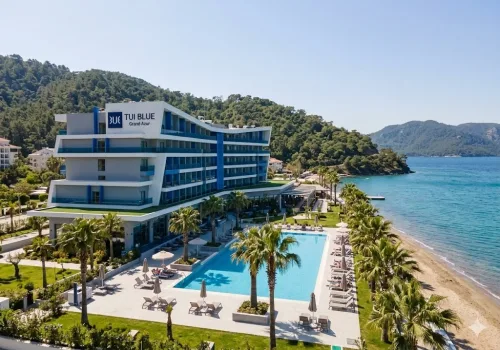 Dalaman Havalimanı'ndan Marmaris TUI BLUE Grand Azur oteline ulaşım sağlayan Ege Vip Tur lüks VIP transfer aracı ve Mavi Bayraklı sahil manzarası.