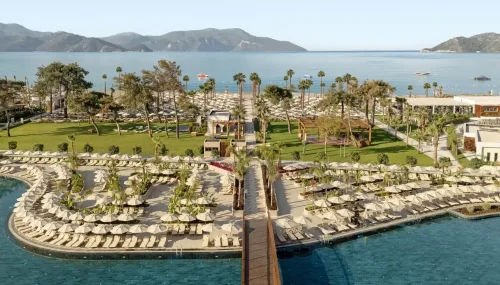 Dalaman Havalimanı'ndan Liberty Signa Fethiye oteline VIP ulaşım sağlayan siyah lüks Mercedes Vito araç, arkaplanda Liberty Signa'nın modern mimarisi ve Koca Çalış sahili.